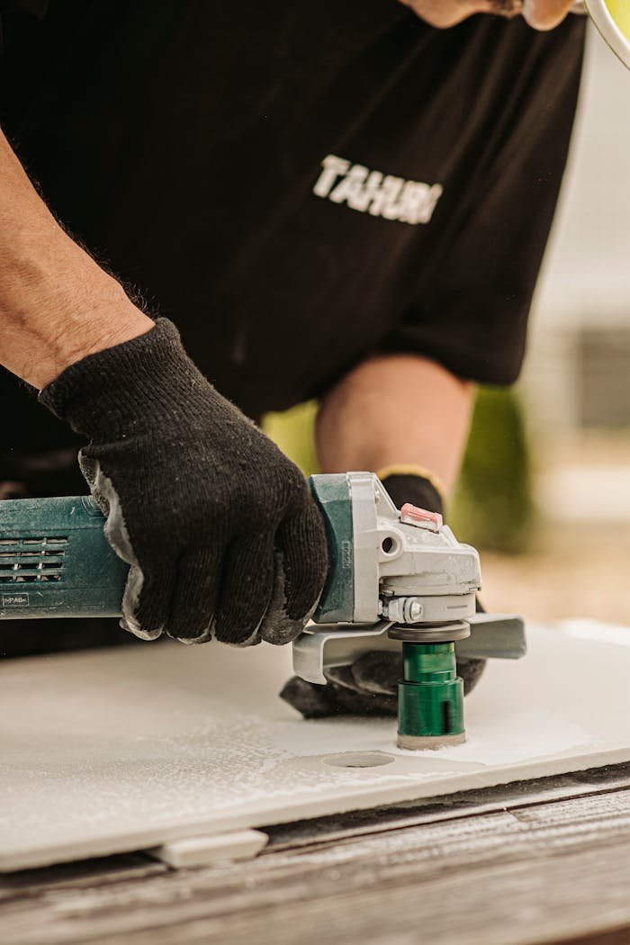 Worker using a power tool with precision outdoors, showcasing skilled craftsmanship.